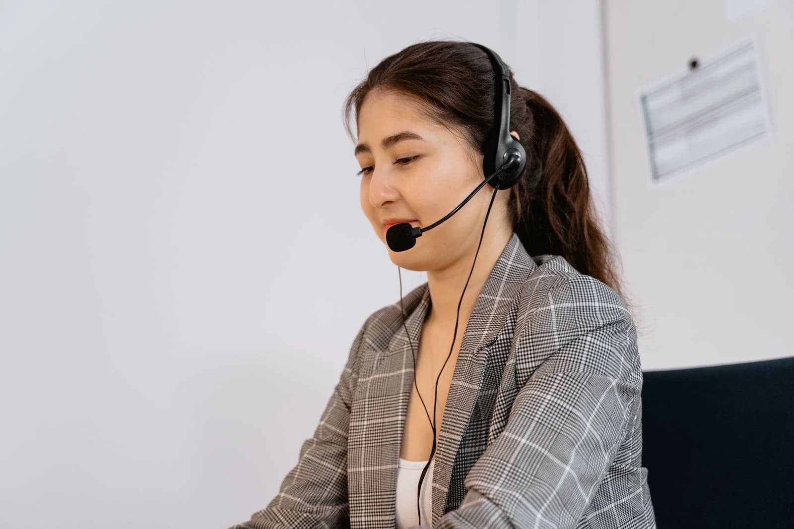 A professional wearing a blazer and a headset with a microphone in an office.