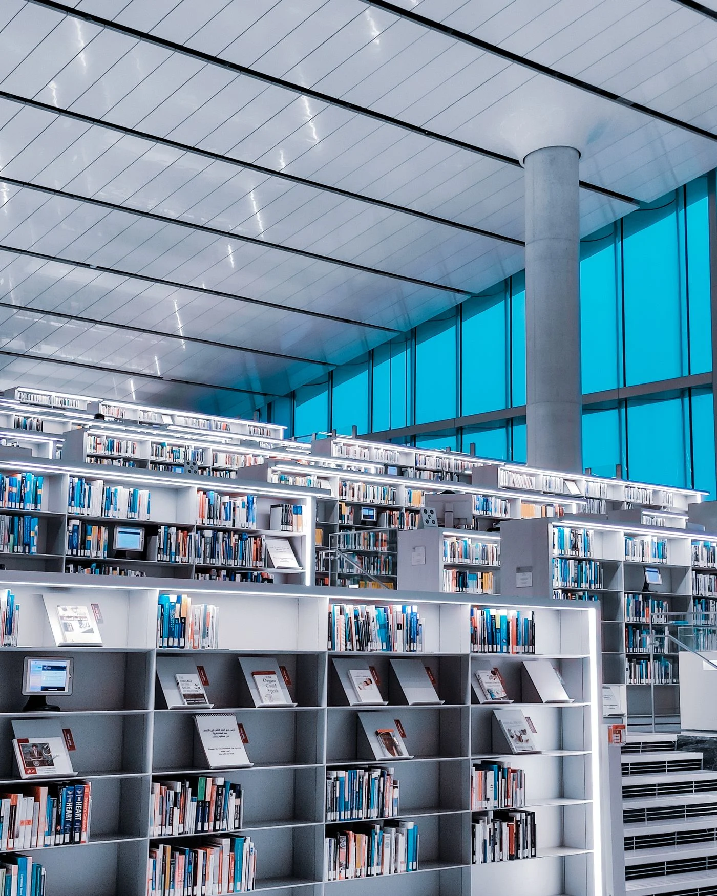 A public library interior with bookshelves, study spaces and large windows.