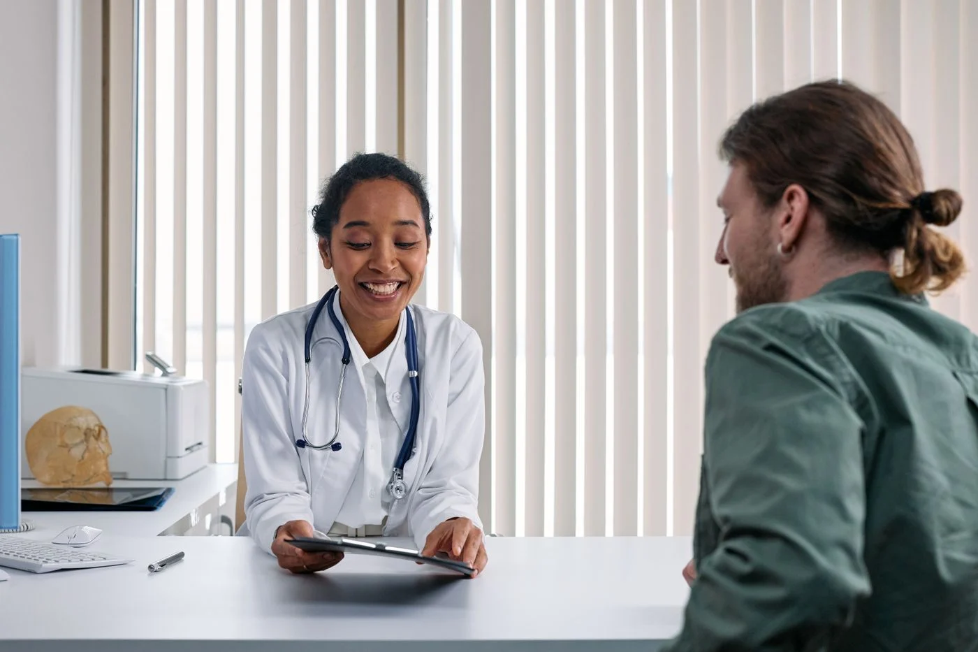 A physician and patient in conversation at a clinic desk.