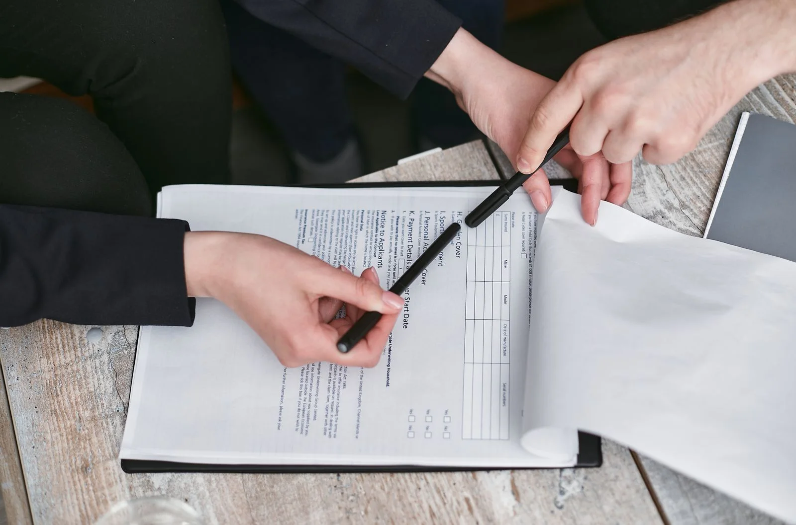 Two people review a printed document together at a desk.