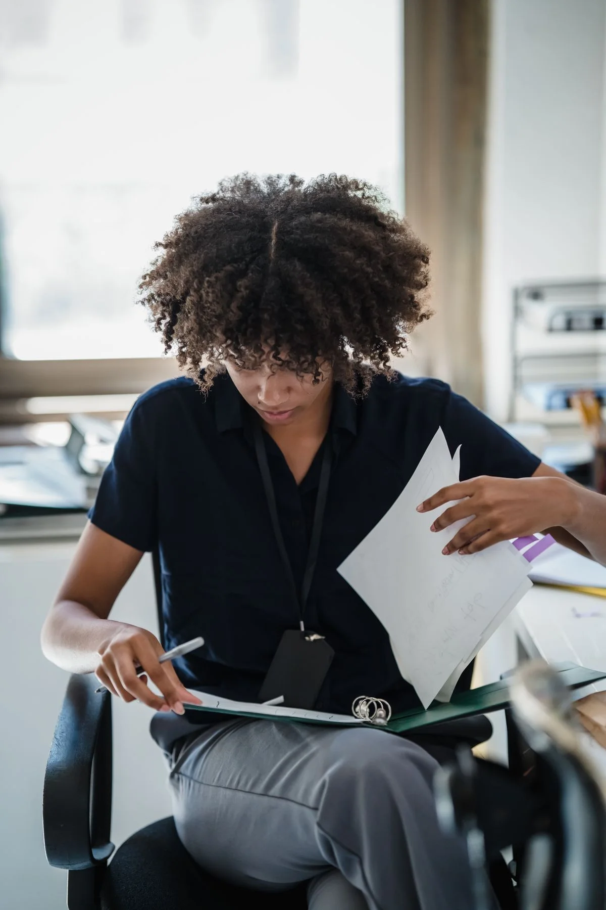 A professional reviewing printed documents and a work folder.