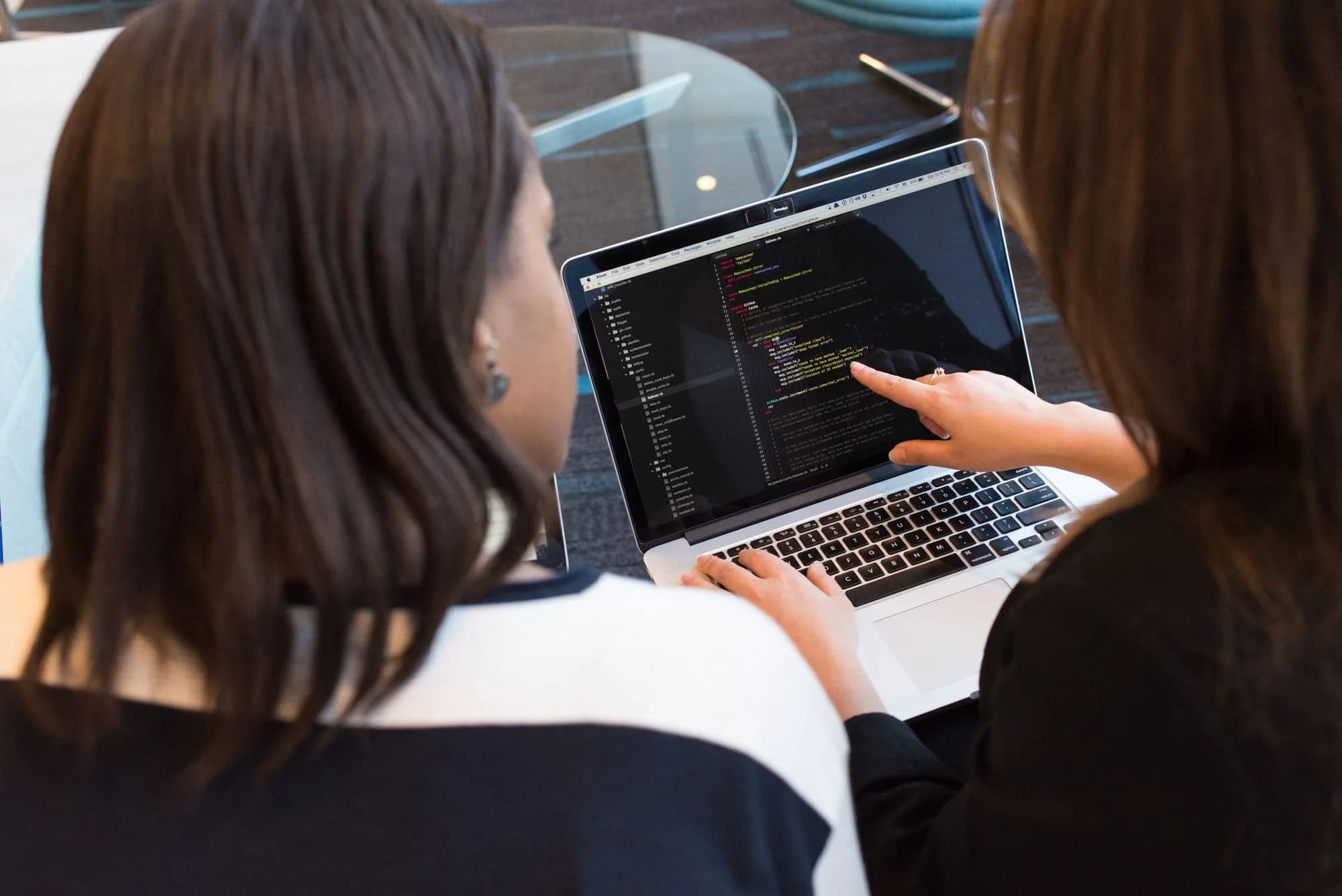 Two professionals reviewing application content on a laptop.